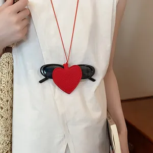 Close-up of a red leather heart-shaped sunglasses holder worn as a stylish necklace