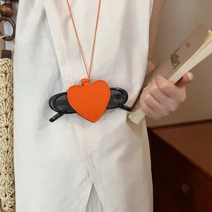 Close-up of orange heart-shaped leather sunglasses case worn as a stylish necklace.