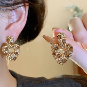 Nahaufnahme von vergoldeten Herz-Ohrsteckern im Vintage-Stil mit Champagner-Zirkonia