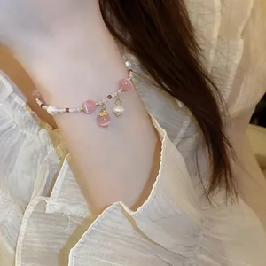 Detail showing the pink cat-eye stone and pearl beads on a delicate handmade bracelet