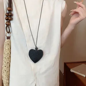 Close-up of black leather heart-shaped pendant sunglasses holder worn as a necklace