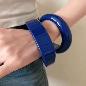 Set di due bracciali rigidi minimalisti in resina blu vibrante indossati al polso.