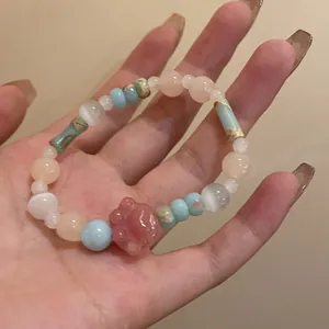 Detailed view of handmade beaded bracelet featuring a pink cat paw charm and catseye beads