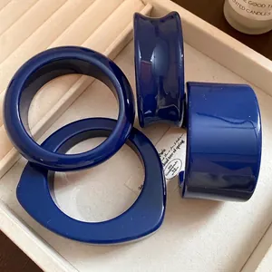 Set di bracciali aperti in resina blu navy presentati in un vassoio per gioielli color crema