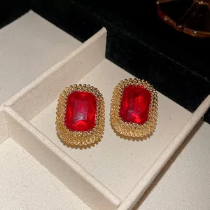 Primo piano di orecchini vintage rettangolari con gemma rossa e bordo dorato in una scatola