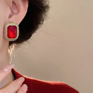 Dettaglio degli orecchini vintage con gemma rossa e cornice dorata alla moda