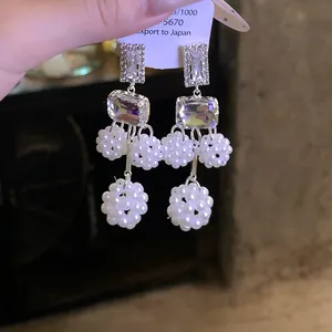Dettaglio di eleganti orecchini geometrici in argento con cristallo e perle bianche