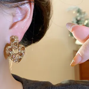 Detailansicht von goldenen Vintage-Herzohrringen mit funkelnden braunen und klaren Zirkonias