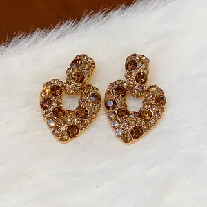 Nahaufnahme von vergoldeten Vintage-Herzohrringen mit funkelnden Zirkoniasteinen.