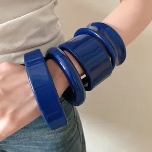 Dettaglio ravvicinato di vistosi bracciali in resina blu indossati da una modella