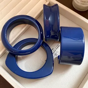 Vista dettagliata di quattro braccialetti in resina blu scuro e un polsino in un vassoio beige