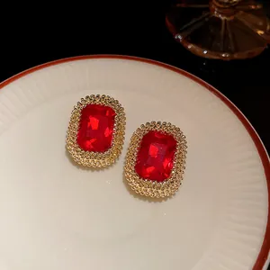 Dettaglio di orecchini vintage con gemma rossa rettangolare e bordo di perline dorate eleganti