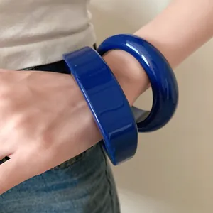 Primo piano di bracciali in resina blu indossati al polso con una finitura lucida