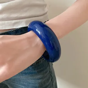 Primo piano di un audace bracciale rigido in resina blu spessa indossato al polso.