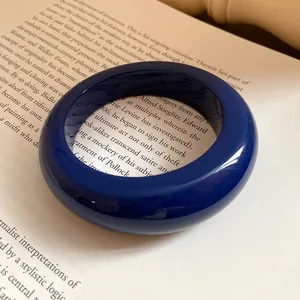 Vista dettagliata di un bracciale in resina blu intenso lucido su un libro aperto.