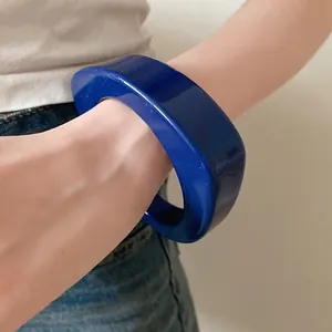Dettaglio di un bracciale rigido in resina blu scuro indossato al polso