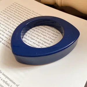Primo piano di un grosso braccialetto in resina blu scuro con design geometrico a goccia