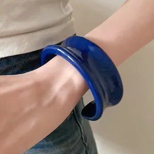 Primo piano di un bracciale a fascia in resina blu reale dal design curvo esagerato.