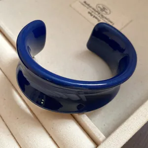 Dettaglio di un bracciale rigido minimalista in resina blu intenso con finitura lucida
