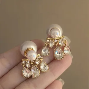 Primer plano de elegantes pendientes de perlas y diamantes de imitación bañados en oro.