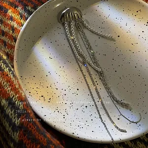 Unique jellyfish brooch with long pearl and rhinestone tassels on a speckled plate