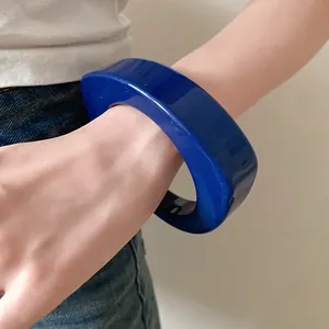 Vista dettagliata di un bracciale rigido in resina blu indossato al polso per lo stile