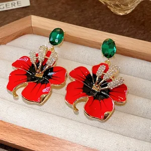 Orecchini a fiore di ibisco con cristalli verde smeraldo e petali in smalto rosso