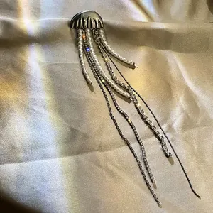 Close-up of elegant jellyfish brooch with dangling pearl and rhinestone tassels