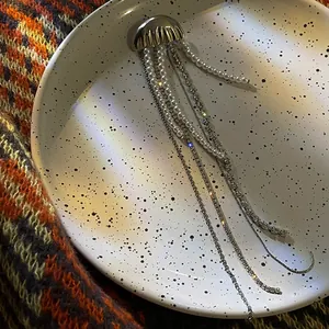 Detail view of jellyfish brooch with pearl and sparkling crystal tassels on ceramic plate