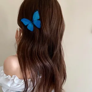 Close-up showing a vivid blue butterfly hairpin texture on wavy brown hair detail view
