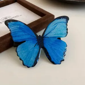 Detail view of a vibrant blue butterfly hair clip with shimmering forest style details.