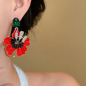 Dettaglio di un orecchino floreale rosso stile vintage con strass indossato da una modella