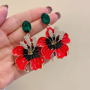 Vista dettagliata degli orecchini a fiore in smalto rosso con cristallo verde e strass.