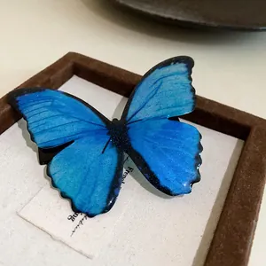 Close-up detail of a vibrant blue butterfly hair clip featuring fine glitter and resin texture