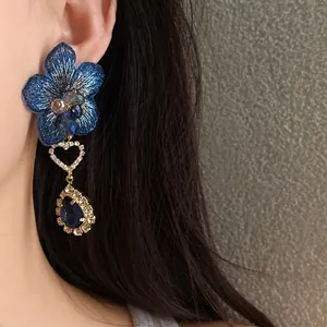 Dettaglio di eleganti orecchini a fiore ricamato blu con pendenti in cristallo