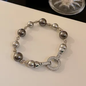 Dettaglio macro del bracciale di perle grigie stile francese con chiusura tonda zirconi