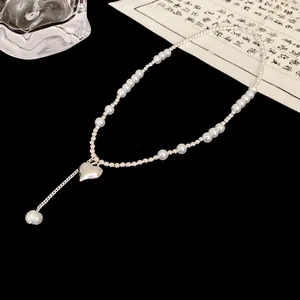 Detailed view of an elegant silver beaded necklace featuring pearls and a heart pendant