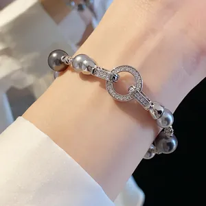 Primo piano di un elegante bracciale di perle con chiusura circolare in zirconi sul polso