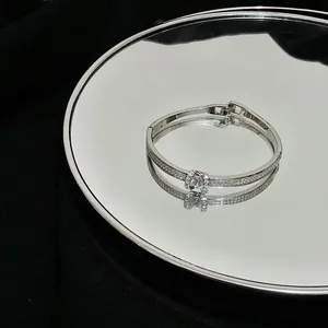 Detail shot of a minimalist silver-tone bangle with pavé-set rhinestones displayed on a mirror.