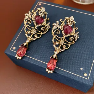 Détail de boucles d'oreilles style palais vintage avec pierres rubis en cœur et goutte