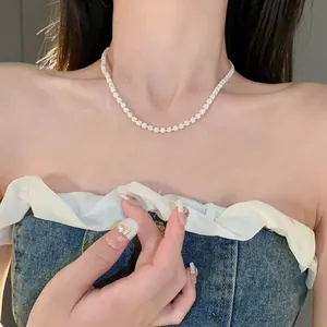 Close-up of minimalist white square beaded necklace with gold accents on model.