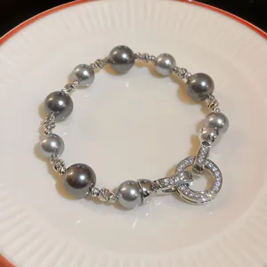 Dettaglio di un bracciale di perle grigie con chiusura decorata con zirconi