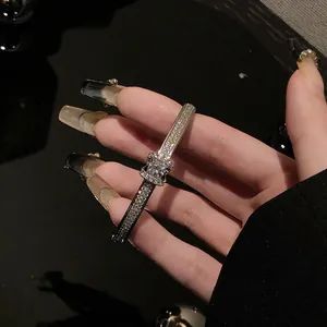 Detail of gold geometric bracelet with square-cut center stone and pave crystals