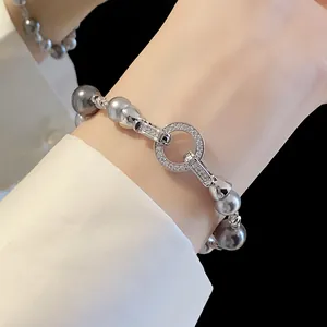 Dettaglio ravvicinato di una chiusura a cerchio con zirconi su bracciale di perle