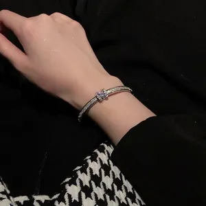 Close-up view of an elegant geometric silver bangle with micro-pave crystals on wrist