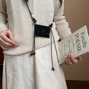 Dettaglio di una catena in vita etnica vintage con mini borsa nera e perle di legno