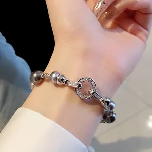 Dettaglio di un elegante bracciale di perle grigie con chiusura a cerchio in zirconi
