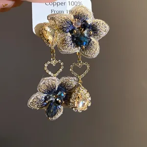 Dettaglio orecchini a fiore ricamati asimmetrici con pendenti a goccia