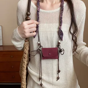 Dettaglio macro di una pochette in tessuto rosso vino retrò e catena in vita con perline.