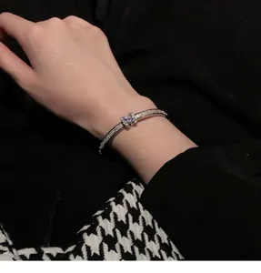 Detailed view of an elegant silver pavé bangle worn on the wrist against black.